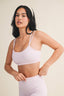 Woman wearing a light pink checkered sports bra and leggings on a beige background
