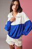 Woman wearing a white and blue color-blocked outfit against a gradient background