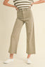 A model wearing high-waisted, wide-leg cropped pants in a light khaki color, paired with a striped top and white sneakers, against a solid cream background.