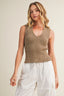 Woman wearing a brown knitted sleeveless top and white pants on a beige background