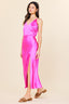 Woman wearing a pink satin dress with a slit on a beige background