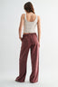 Woman wearing a white tank top and maroon pants on a white background