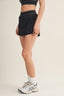 Person wearing a black skirt with white trim on a plain background