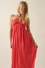 Woman wearing a coral dress against a plain background