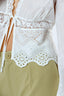 Woman wearing a white lace top with a plain background