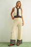 Woman wearing a sleeveless top and wide-leg pants with a striped pattern on a plain background