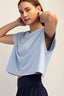 Woman wearing a light blue top with a cutout design on a beige background