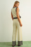 Woman wearing a cream-colored knit jumpsuit with black stripes on a plain background