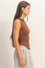Woman wearing a brown sleeveless top and gray sweatpants on a plain background