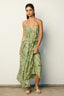 Woman wearing a green and white patterned dress against a plain background