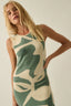 Woman wearing a green and beige patterned dress against a plain background