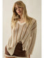 Woman wearing a beige knitted cardigan over a white top with a brown skirt on a plain background