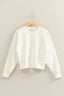 White sweater on a wooden hanger against a beige background