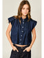 Woman wearing a sleeveless denim shirt against a plain background
