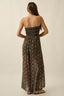 Woman wearing a strapless, long, patterned dress against a plain background