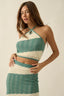 Woman wearing a green and white knitted two-piece outfit on a beige background