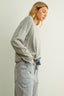 Woman wearing a gray oversized sweatshirt and striped pants against a plain background