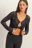 Woman wearing a black lace long-sleeve top and black leggings on a white background