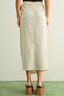 Person wearing a beige skirt with a plain background