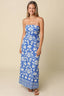 Woman wearing a blue strapless dress with white floral pattern on a beige background