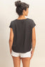 Woman wearing a black top and white shorts against a beige background
