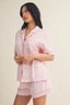 Woman wearing a pink pajama set with a plain background