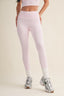 Person wearing light pink leggings and white sneakers on a beige background
