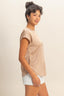Woman wearing a beige top and light-colored shorts on a plain background