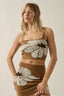 Woman wearing a brown dress with white floral patterns on a beige background