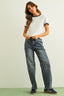 Woman wearing a white t-shirt with black trim and blue jeans on a plain background
