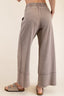 Person wearing light gray wide-leg pants on a plain background