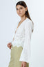 Woman wearing a white lace top with a plain background