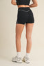 Person wearing black athletic shorts on a beige background