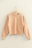 Beige sweatshirt on a wooden hanger against a beige wall