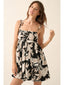 Woman wearing a black and white floral dress against a plain background
