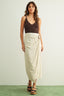 Woman wearing a brown top and beige wrap skirt against a white background