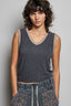 Woman wearing a black ribbed tank top with beige trim against a gray background