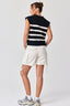 Person wearing a black and white striped sleeveless top and beige shorts on a white background