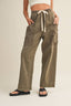 Person wearing olive green cargo pants with a beige background