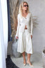 Woman in a white outfit standing in a minimalistic room with decorative elements.
