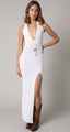 Woman wearing a white halter neck dress with a slit, standing against a plain background.