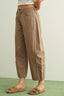 Person wearing brown pants and sandals on a green floor with a light background