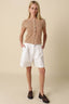 Woman wearing a striped shirt and white shorts on a beige background