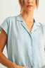 Light blue short-sleeve blouse worn by a person on a plain background