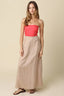 Woman wearing a red strapless top and beige long skirt on a beige background