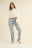 Woman wearing a white shirt and light blue jeans on a beige background