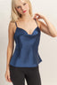 Woman wearing a blue satin camisole against a plain background