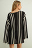 Woman wearing a black and white striped dress against a plain background