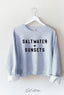 Light blue sweatshirt with 'SALTWATER + SUNSETS' text on a white hanger against a white background