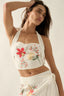 Woman wearing a white embroidered top and skirt against a plain background